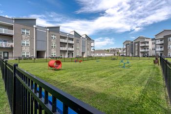 Apartment complex with a green lawn and playground equipment.